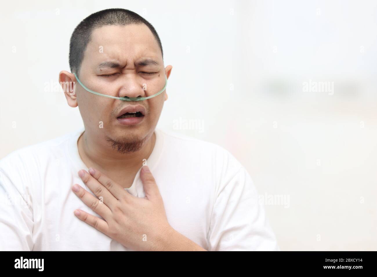 Asian man having asthma and hard to breathing while his hand touching chest against white background. Covid-19 patient in hospital suffer from respira Stock Photo