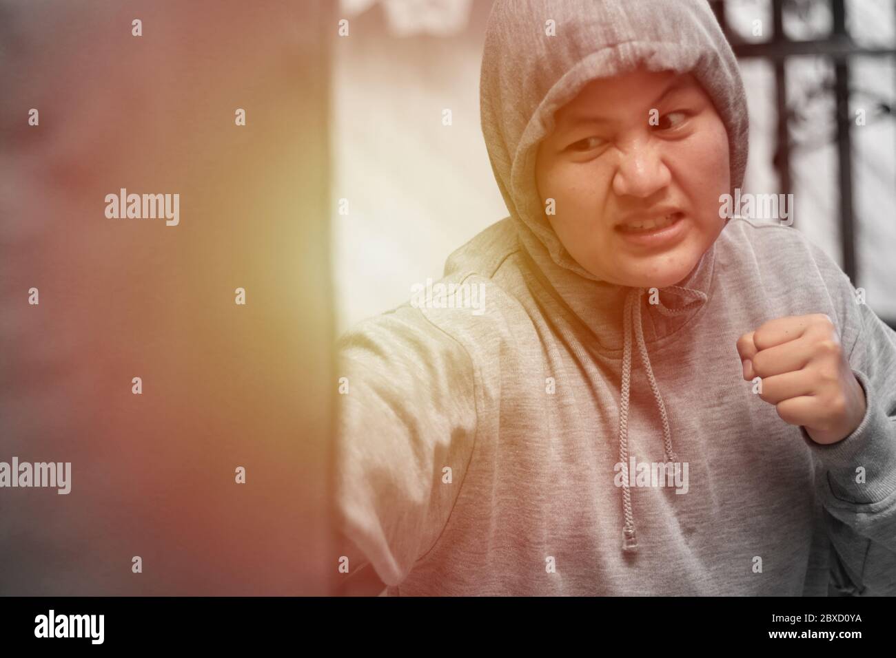 Asian woman boxer hitting punching bag, workout at home gym, female practice martial arts self