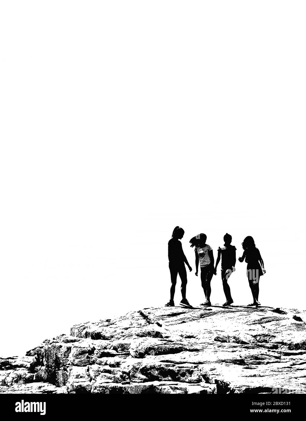 Silhouette of four girls on a large rock. Stock Photo