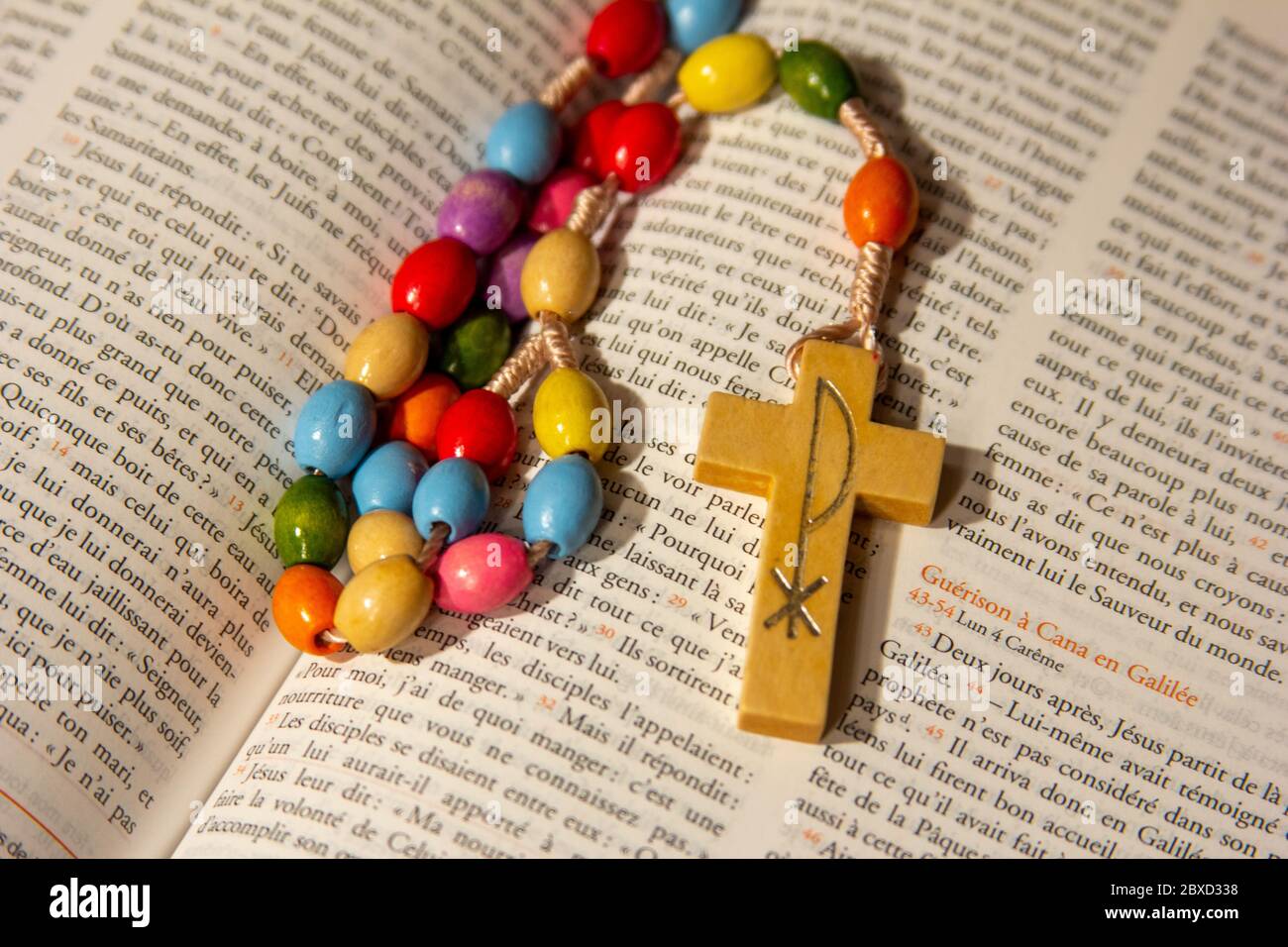 A rosary in an open Bible in French. Stock Photo