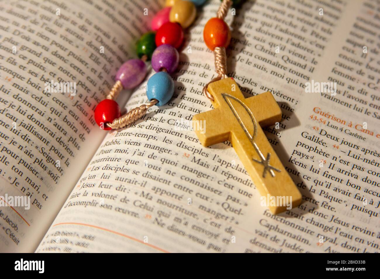 A rosary in an open Bible in French. Stock Photo