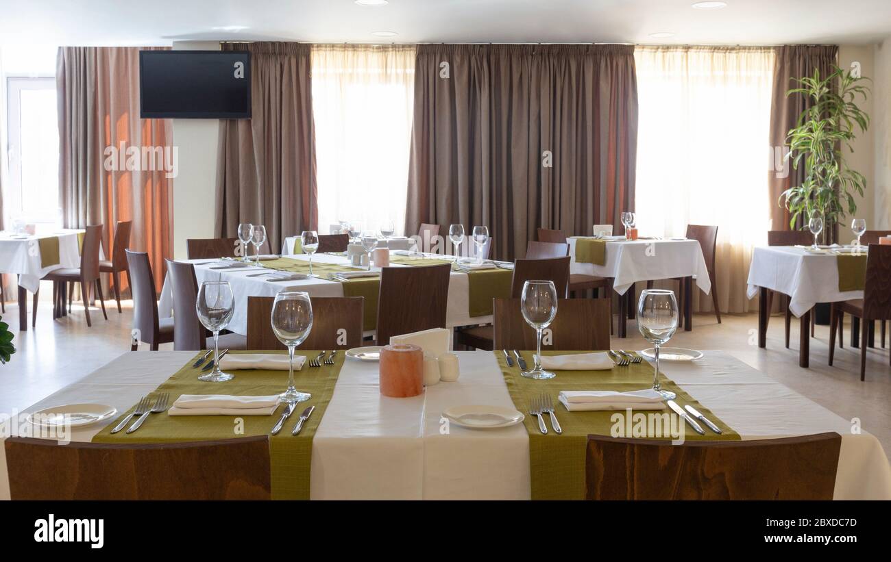 Table ready for guests in interior restaurant with brown curtains Stock Photo