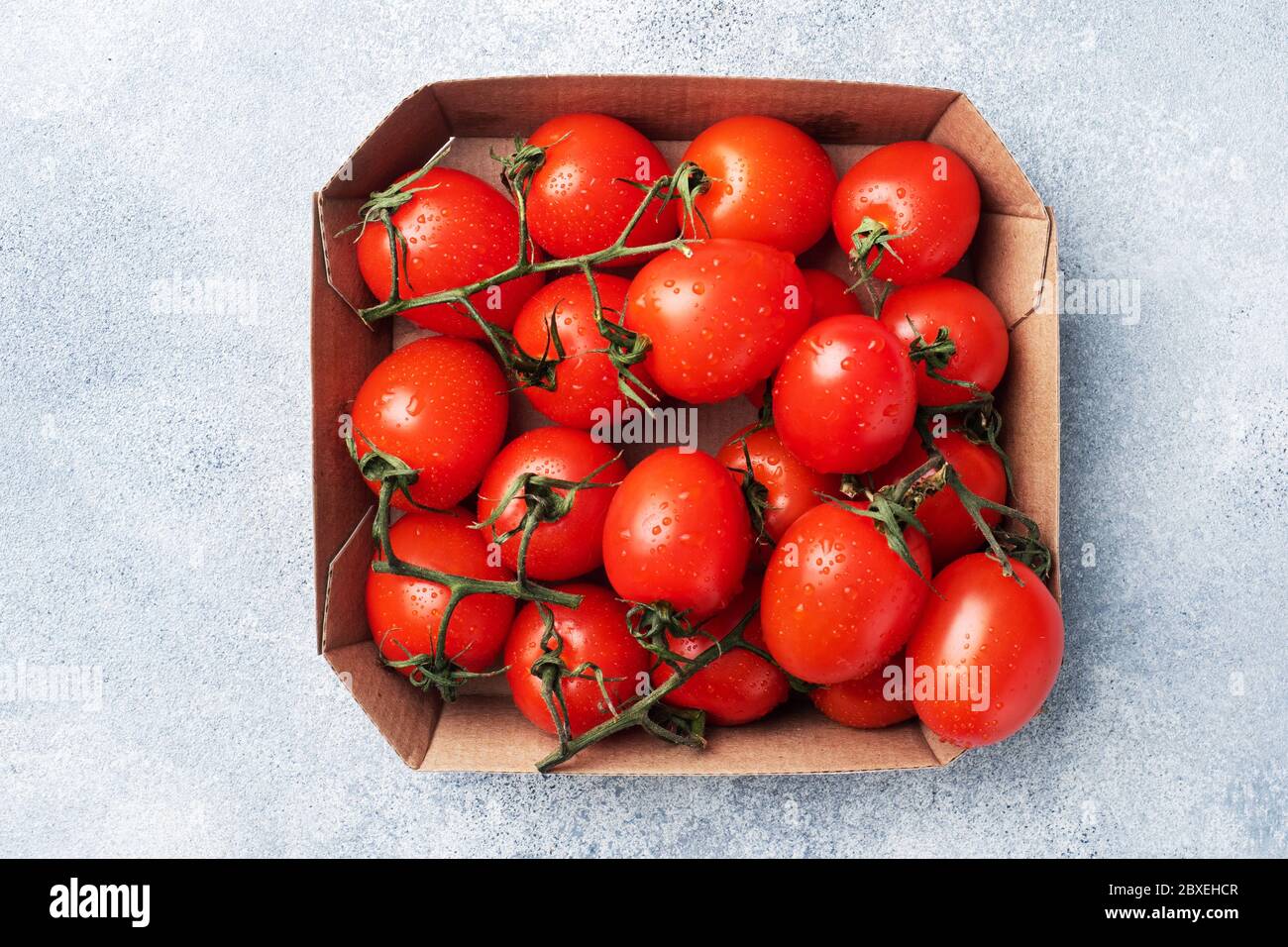 Ripe fresh cherry tomatoes on a branch in a cardboard package Copy space. Stock Photo