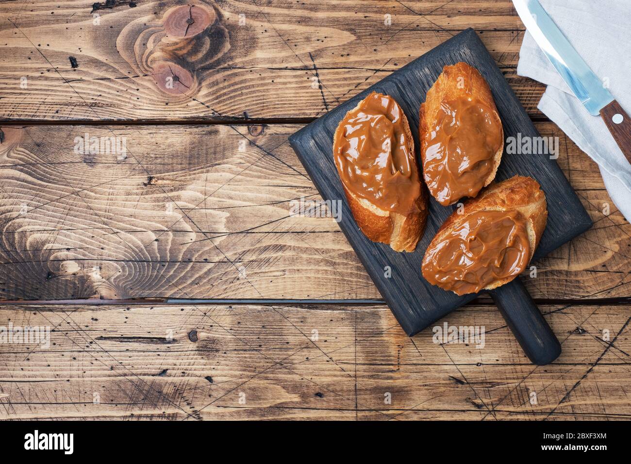 Sandwiches with baguette of bread spread with sweet paste of boiled condensed milk. Wooden background Copy space. Stock Photo