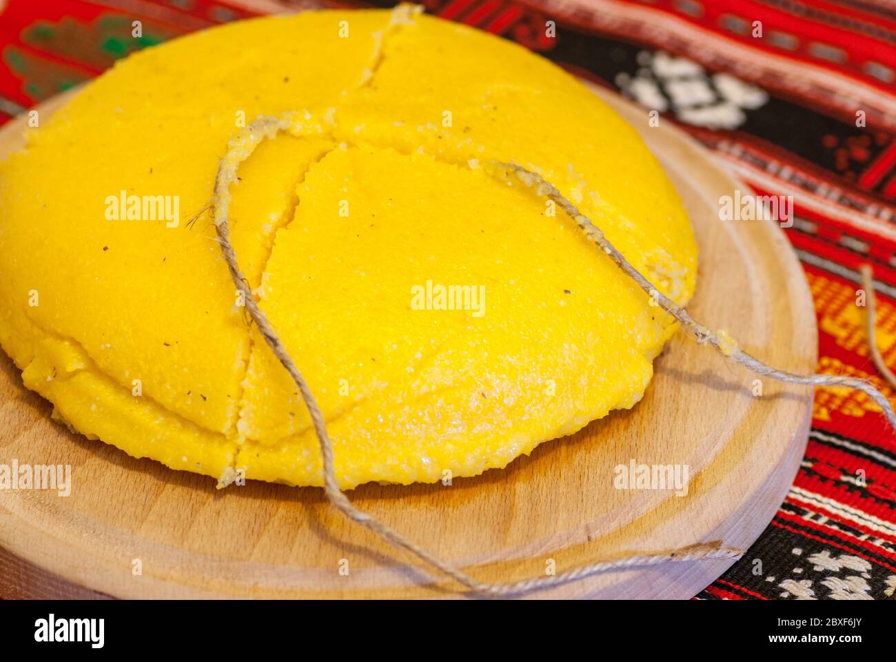 omanian traditional dish polenta mamaliga on wooden plate sliced with a string Stock Photo