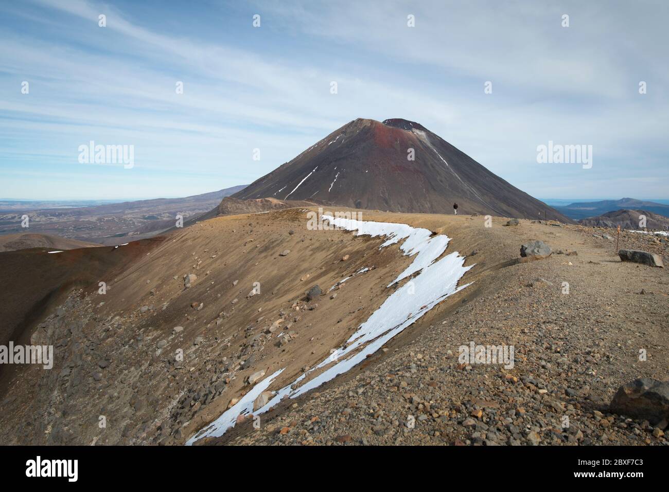View of Mount Ngauruhoe in the distance with one person on the track on the Tongariro Alpine Crossing Stock Photo