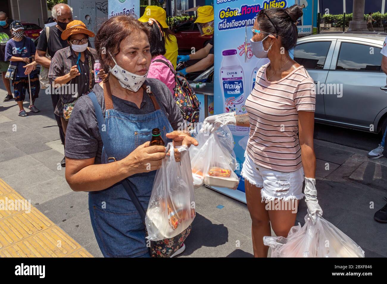 Volunteers with face masks and gloves giving free food at street kitchen during Covid pandemic, Bangkok, Thailand Stock Photo