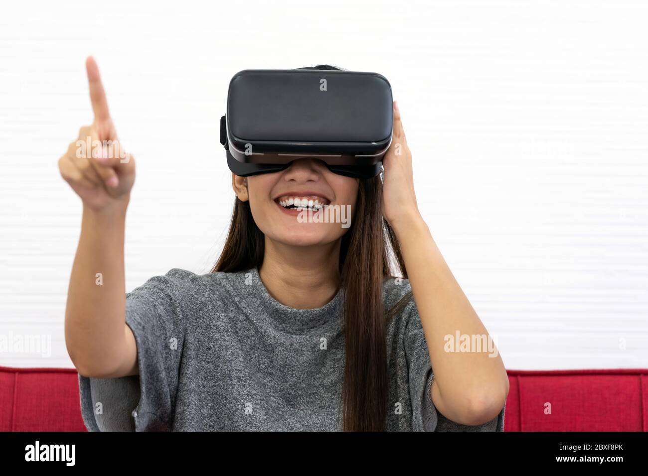 Asian teen beautiful girl woman touching air during playing VR video games experience in living room house for good mental health while quarantine. Ga Stock Photo
