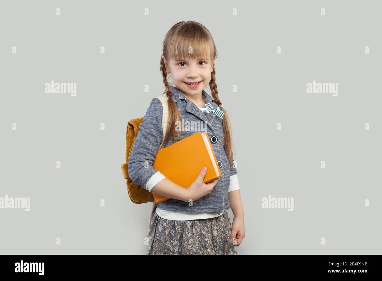 Happy smiling child girl with school bag and book. Back to school ...