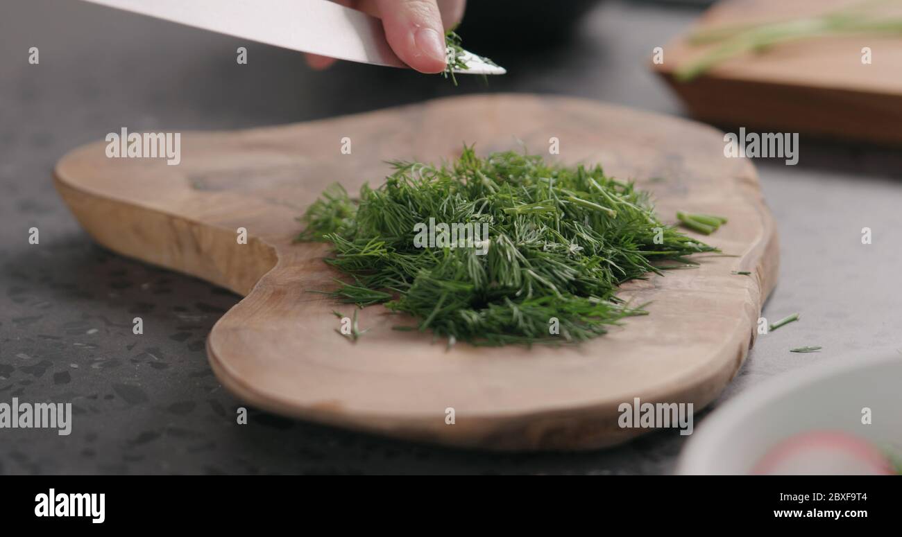 fresh chopped dill on olive board side view Stock Photo