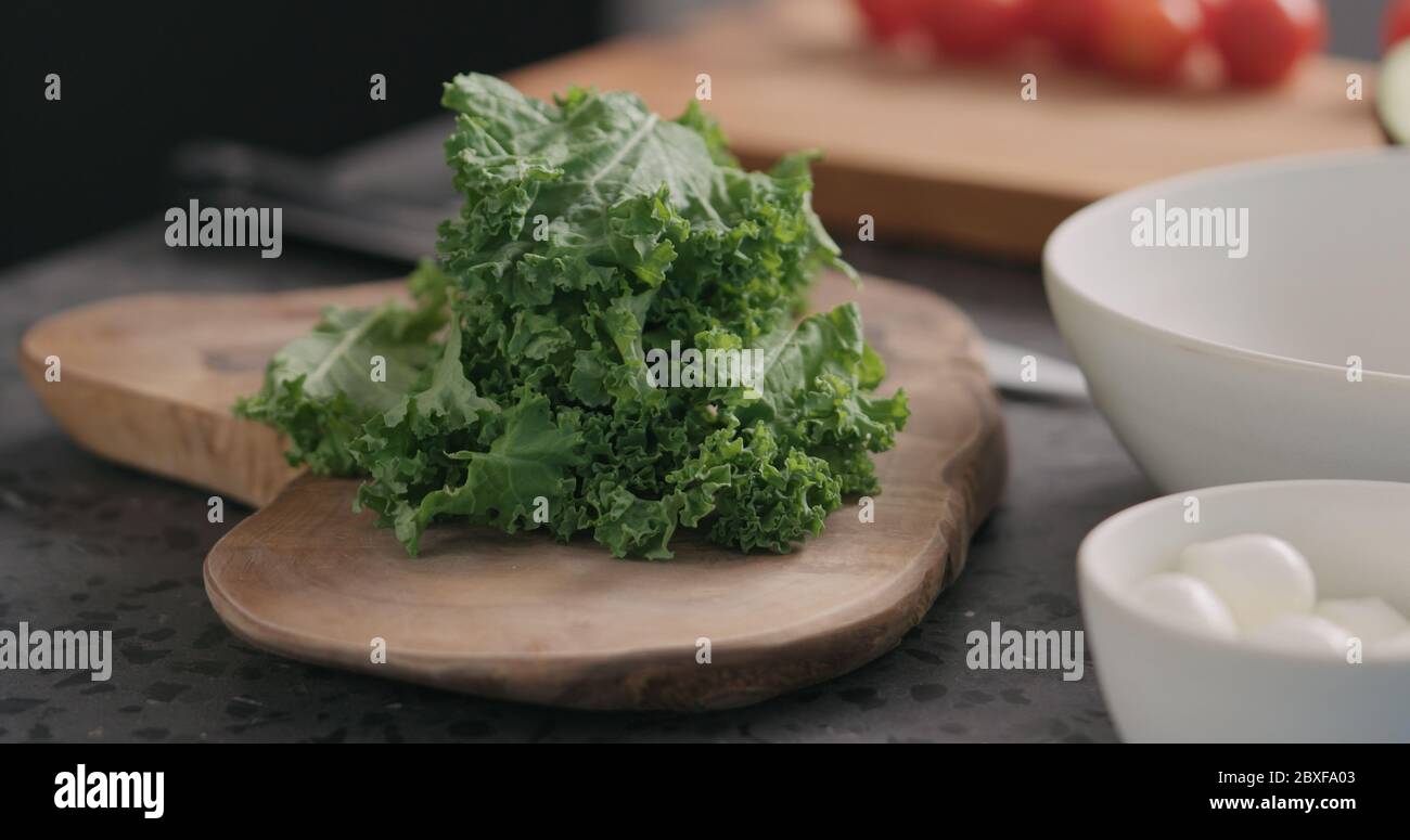 man tearing kale leaves to make it softer for salad on kitchen side view Stock Photo