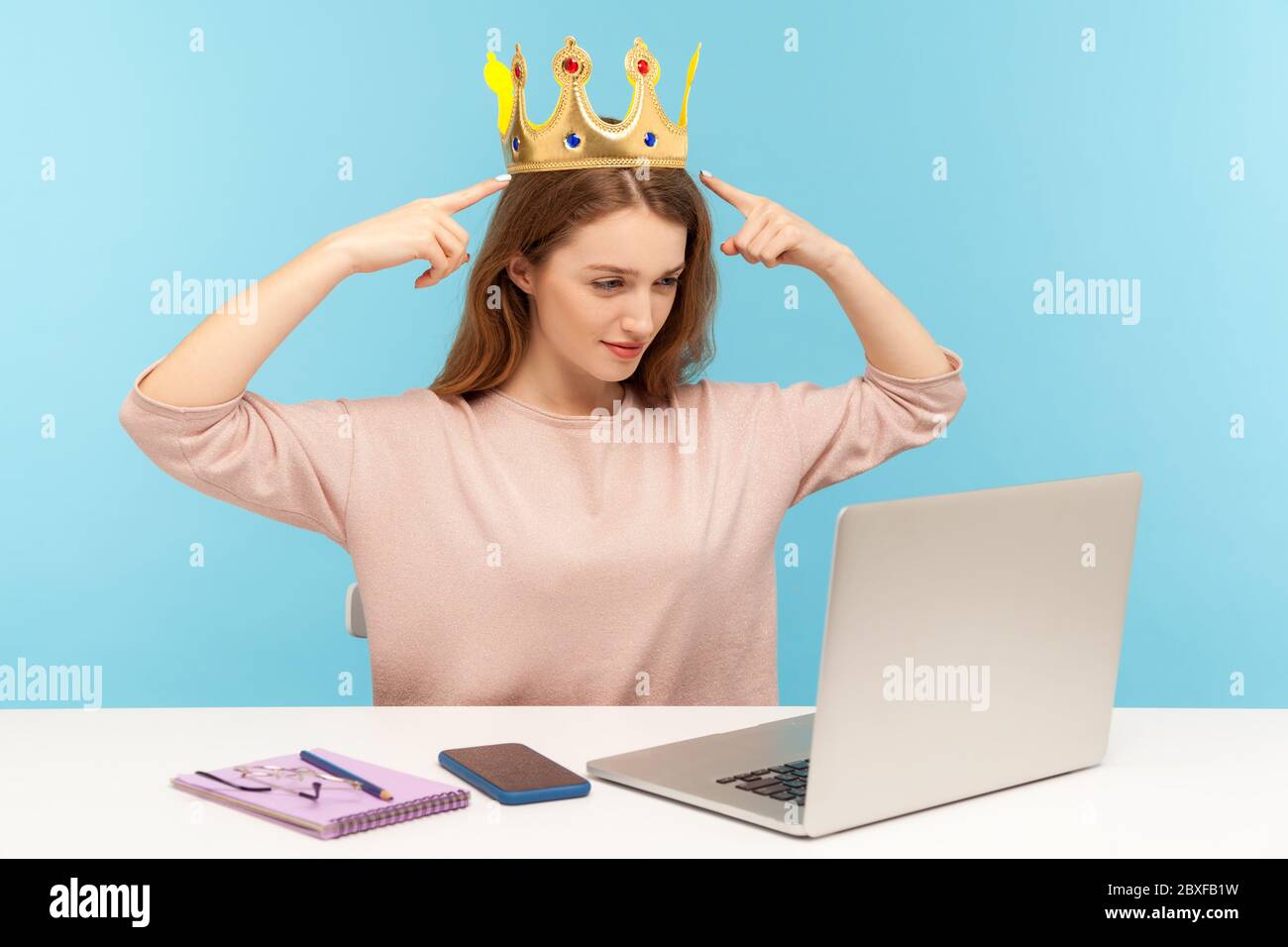 Look, I am the best! Proud egoistic narcissistic woman pointing crown on head and talking on video call laptop screen, expressing over-inflated ego. i Stock Photo
