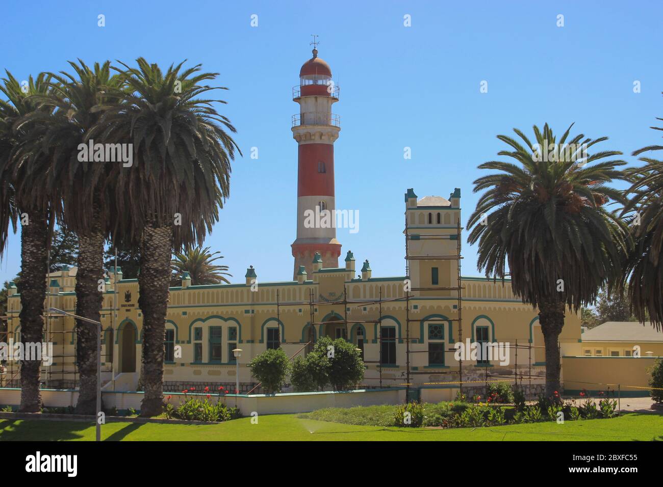 Swakopmund, Namibia - April 18, 2015: Old German red and white lighthouse, which is called "bacon" surrounded by palm trees Stock Photo