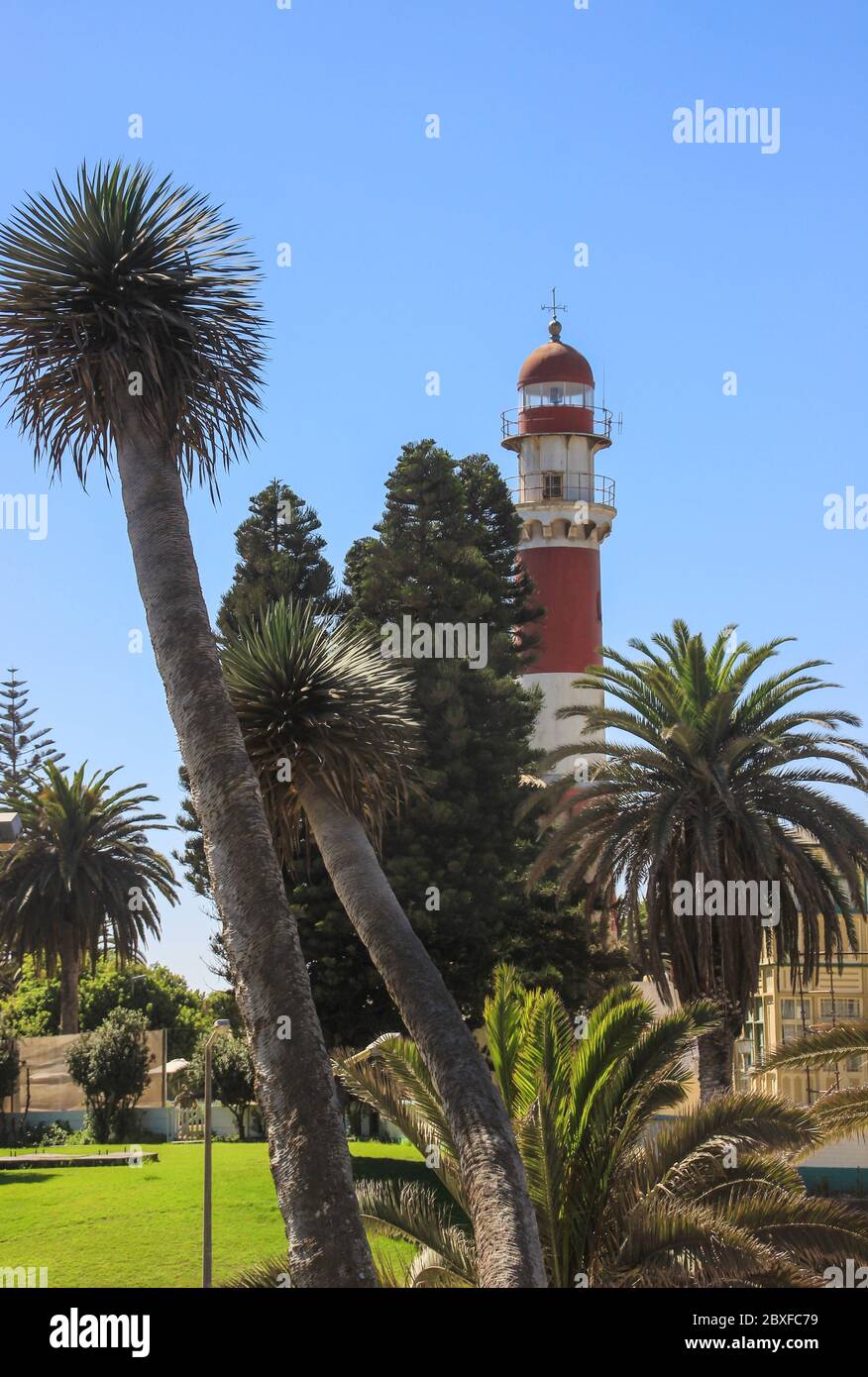 Swakopmund, Namibia - April 18, 2015: Old German red and white lighthouse, which is called "bacon" surrounded by palm trees Stock Photo