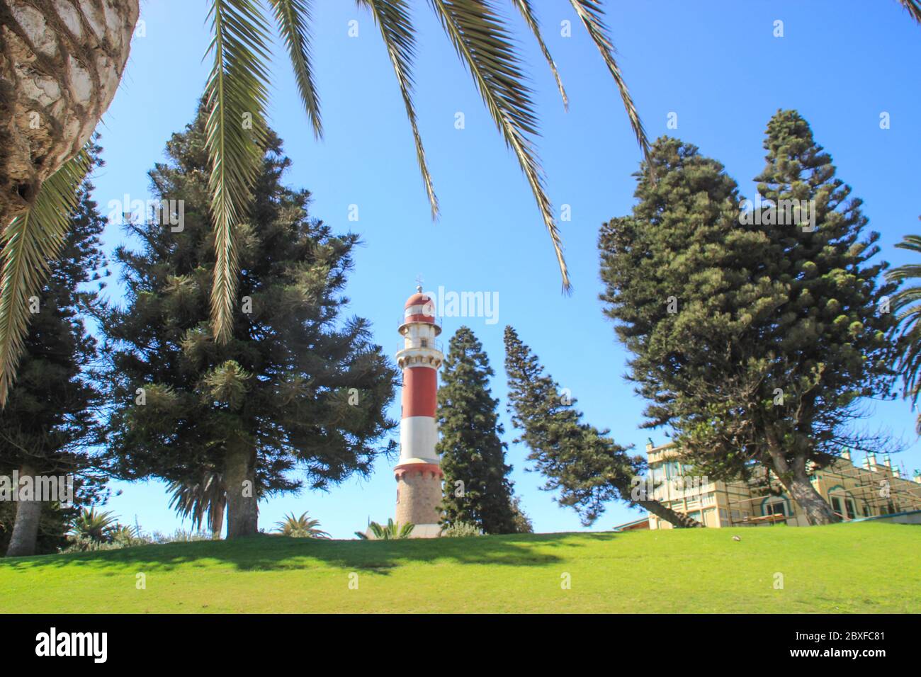 Swakopmund, Namibia - April 18, 2015: Old German red and white lighthouse, which is called 'bacon' surrounded by palm trees Stock Photo
