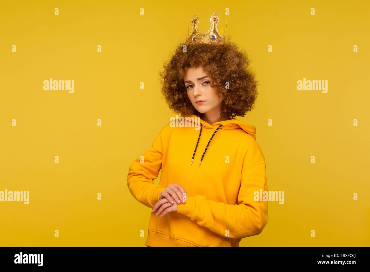 I am queen! Selfish haughty curly-haired woman wearing crown on head and looking with arrogance supercilious, being egoistic with over-inflated ego. i Stock Photo