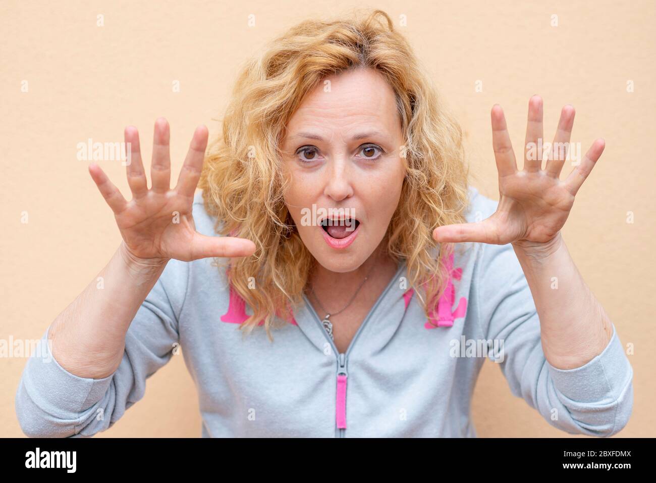 A white woman makes a funny expression by raising her hands close to her face Stock Photo