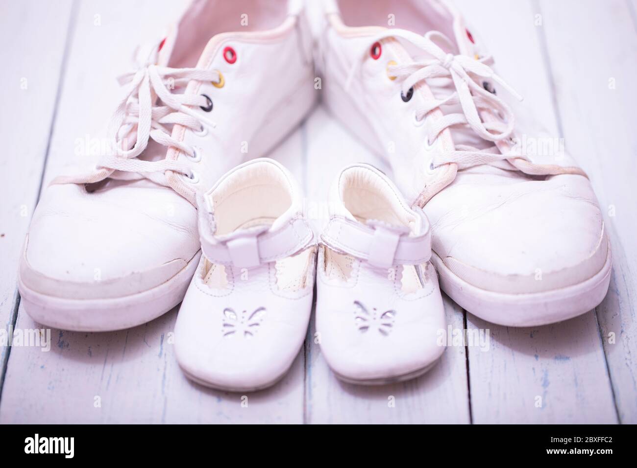 Daddy's baby's sneakers, on white wooden background, fathers day concept. Stock Photo