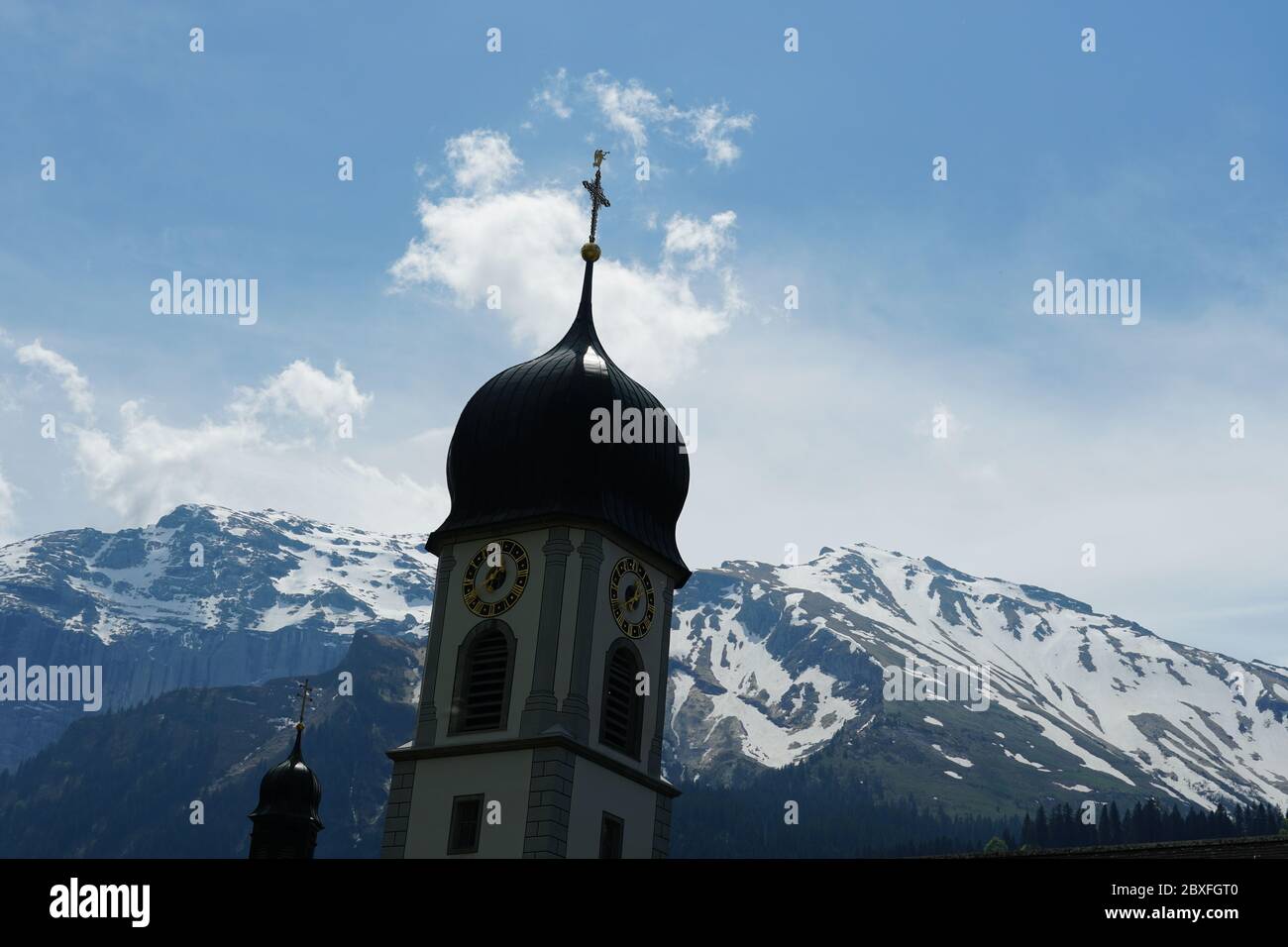 A church bell tower on the background of Alps landscape in Switzerland ...