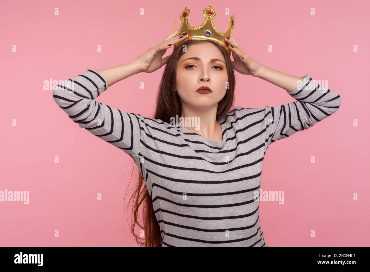 I'm leader! Portrait of ambitious successful woman adjusting golden crown on head and looking with arrogance, declaring her authority, superiority. in Stock Photo