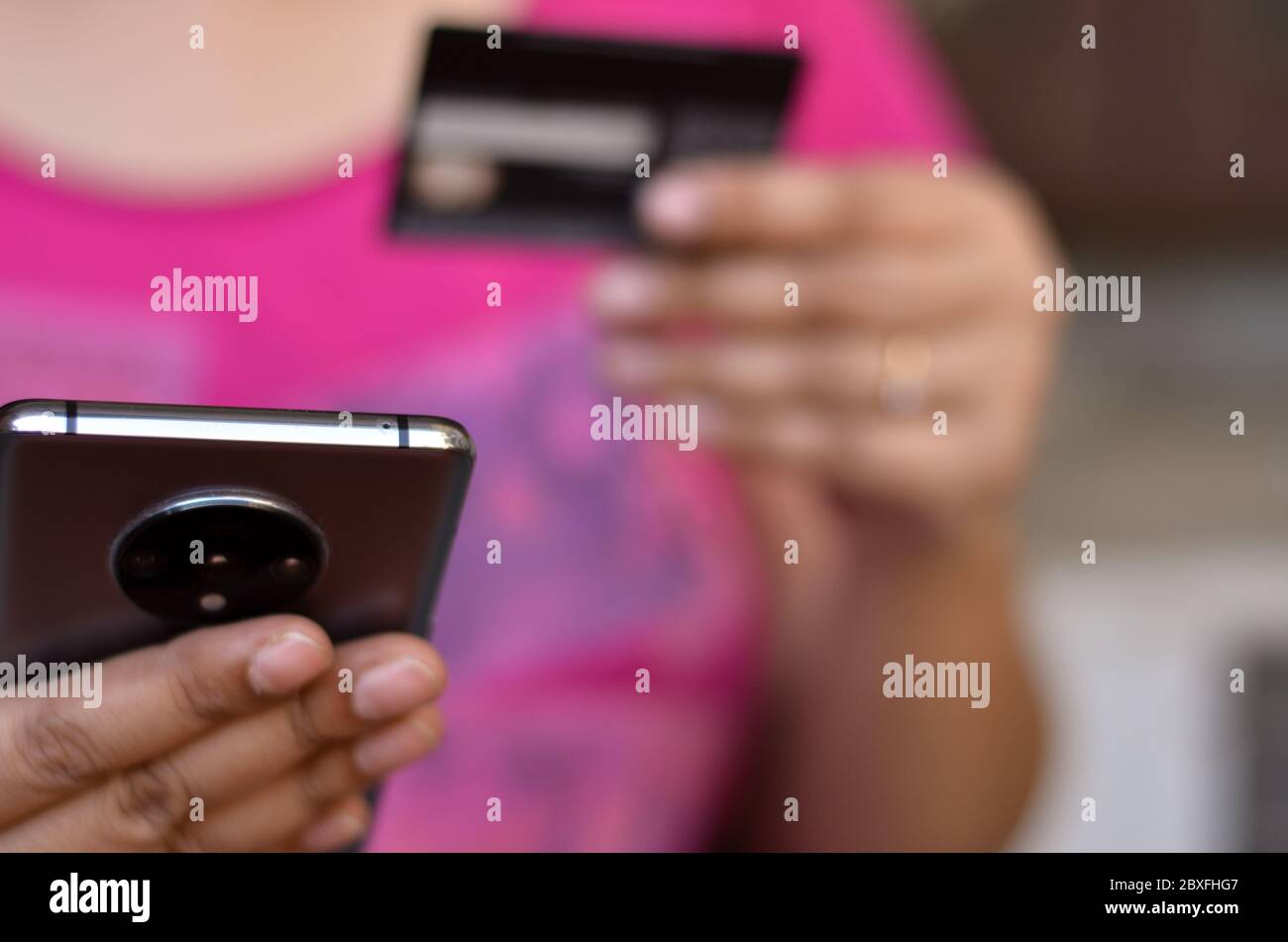 Shot of a woman looking at her smartphone and doing digital payment with her credit or debit card in her left hand. Concept - Digital finance and Fint Stock Photo