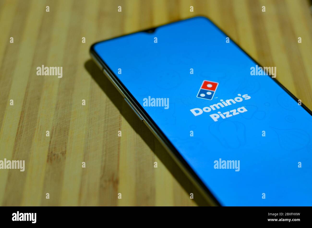 New Delhi, India, 2020. Flat lay mobile phone showing Domino's pizza delivery mobile app during on a wooden board background. Delivery of food is allo Stock Photo