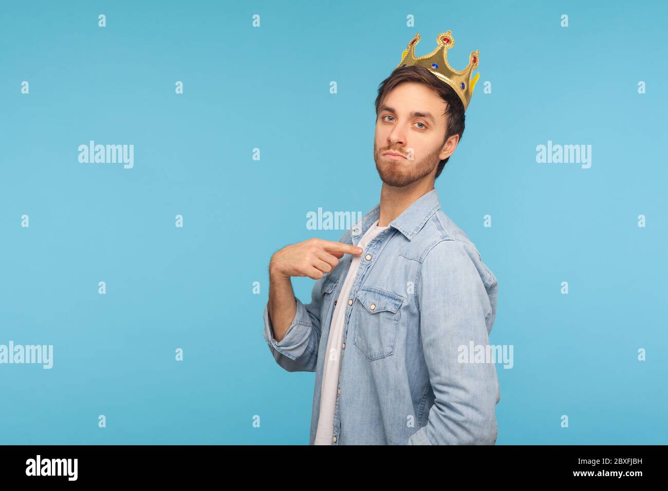 I'm king! Portrait of ambitious man wearing golden crown and pointing himself, looking with arrogance, declaring his authority, superior privileged st Stock Photo