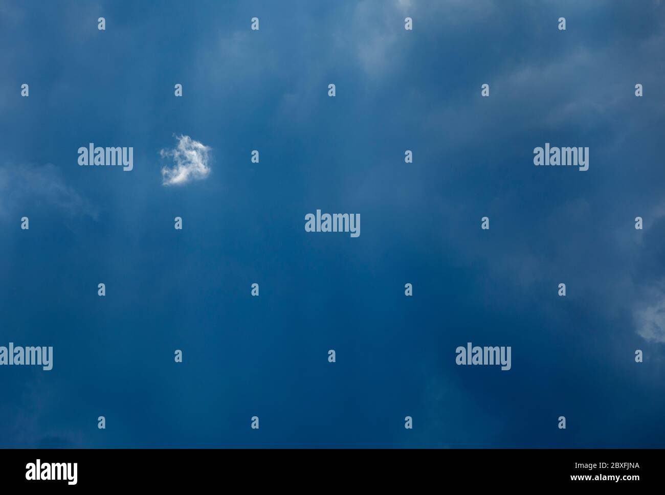 One tiny white cloud on dark grey sky Stock Photo