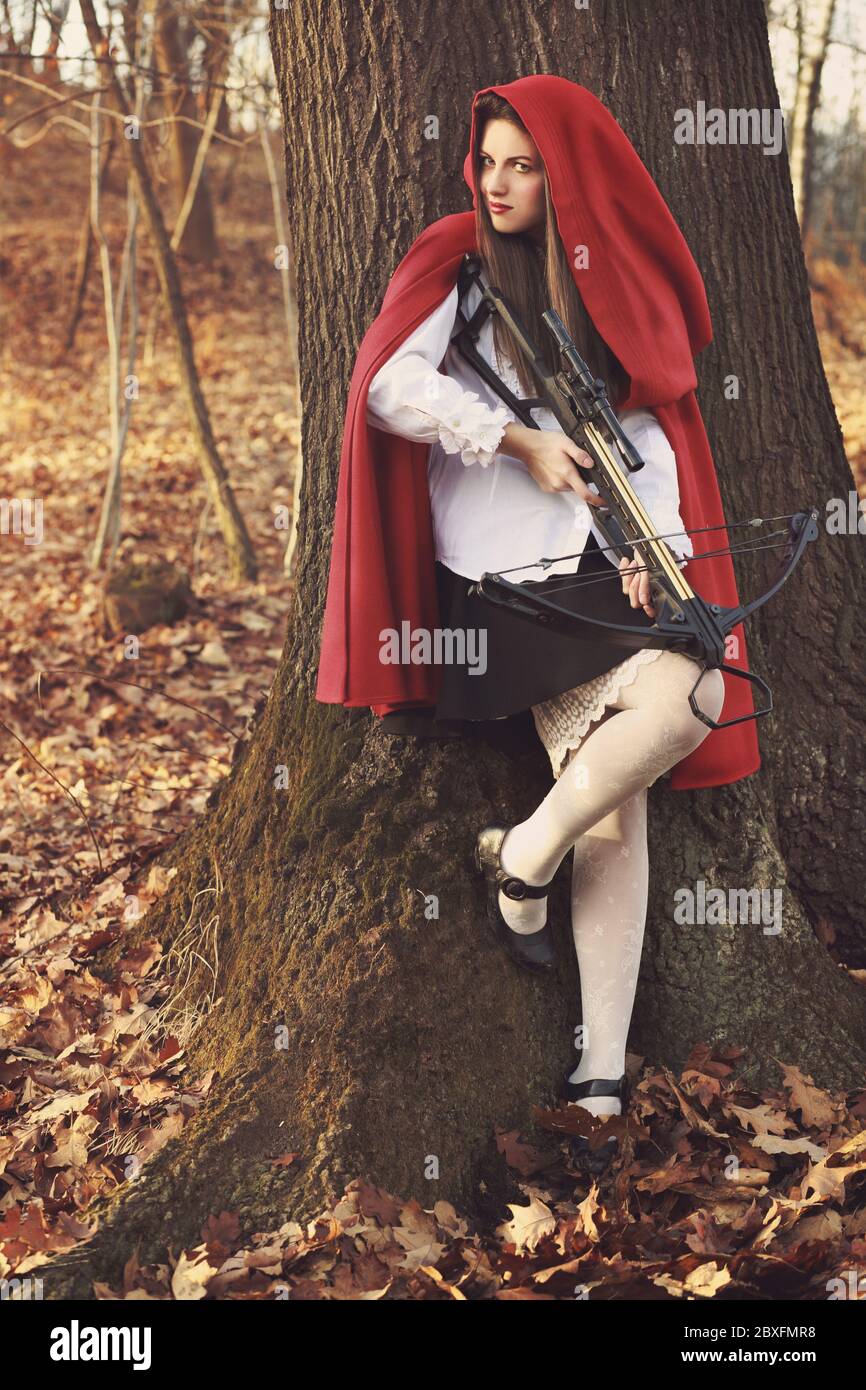 Little red riding hood leaning to a tree and waiting her prey Stock Photo