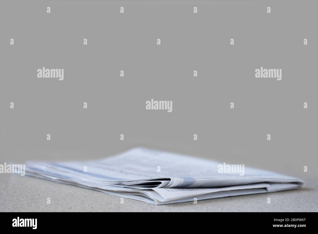 Newspaper against plain background with narrow depth of field. Gray background Stock Photo