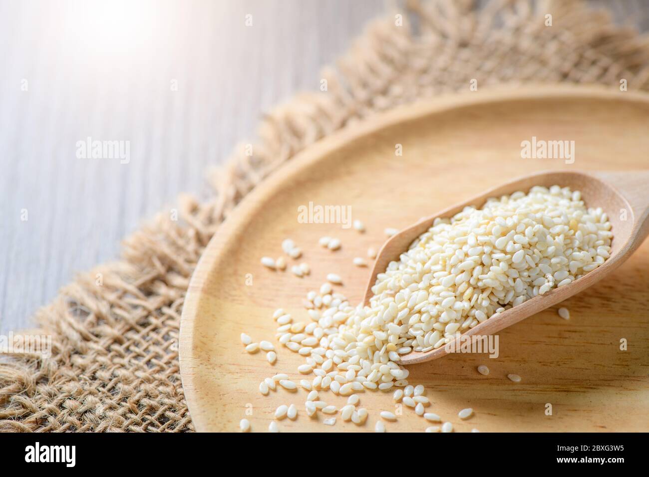 White sesame seeds in a wooden spoon on wood table. White sesame is rich in calcium and