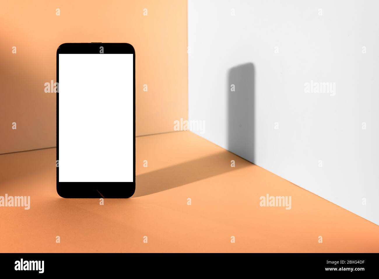 Minimalist modern smartphone mockup for presentation, in perspective front of the corner angle of the peach wall, with overlapping shadows. applicatio Stock Photo