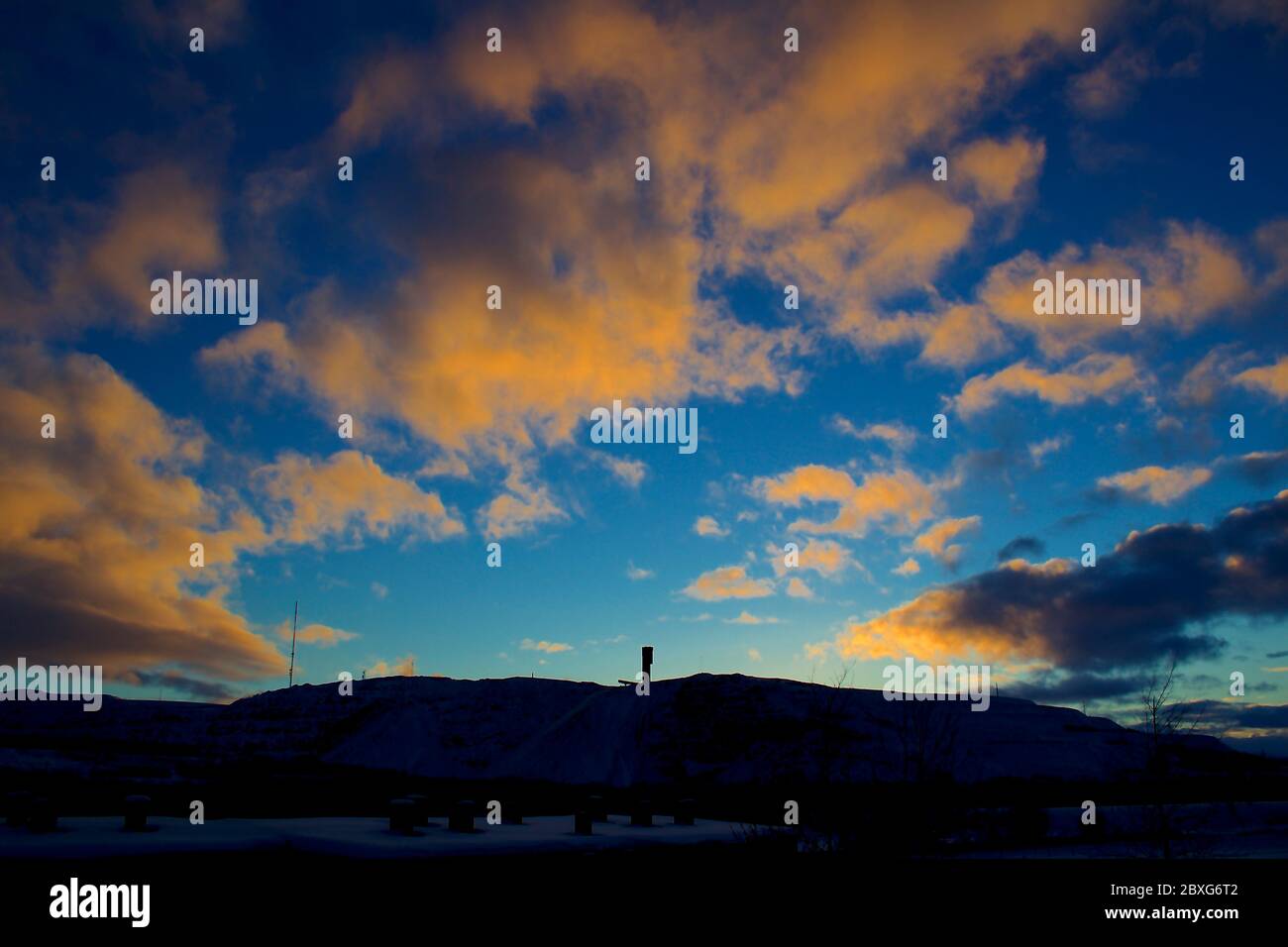 Silhouette of Kiruna iron ore mine with beautiful orange twilight sky in the background Stock Photo