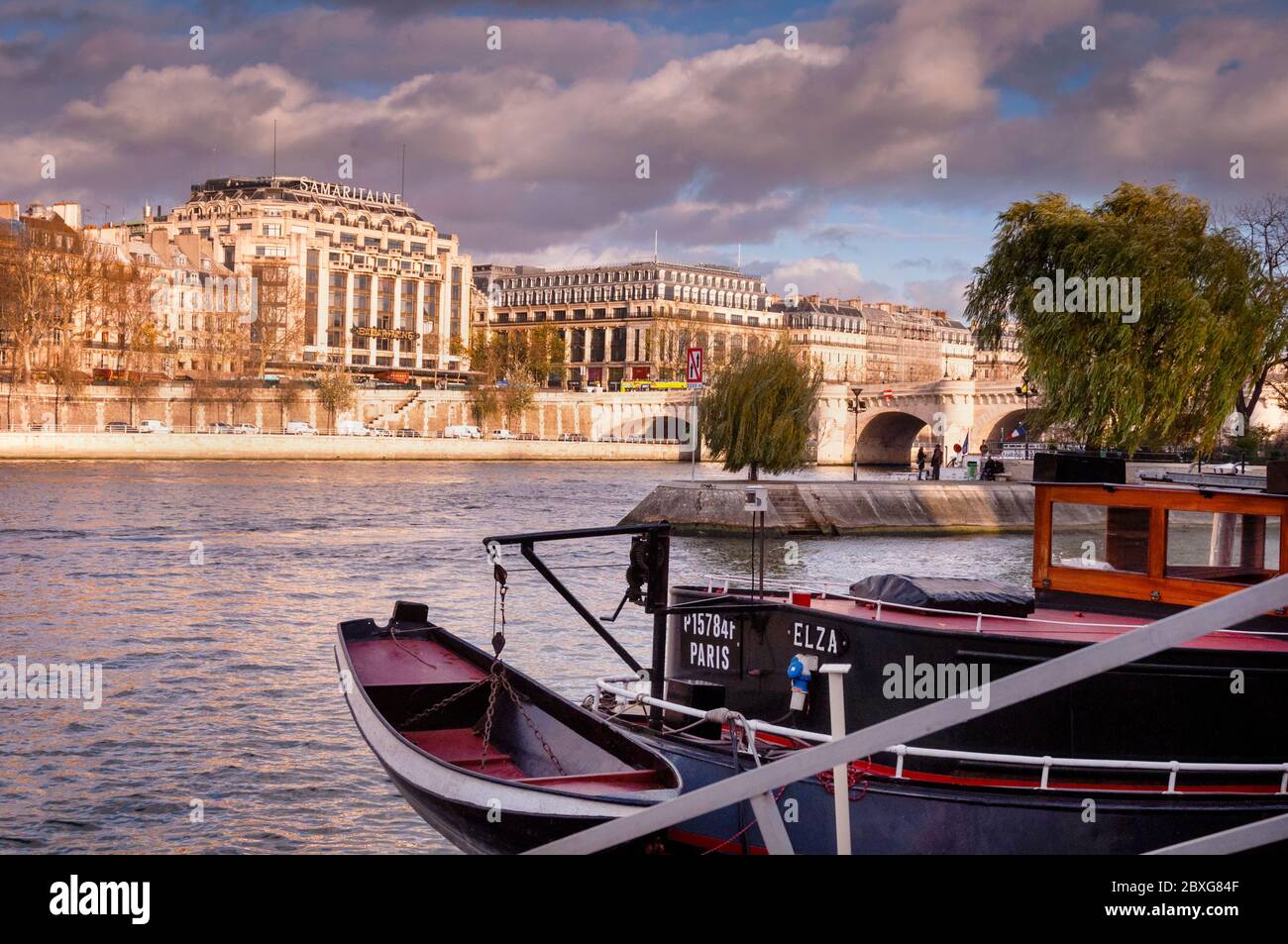 A wood boat has a prime parking space on the Seine River in Paris, near the  Pont Neuf arched stone bridge and Île de las Cité, the heart of the city  Stock
