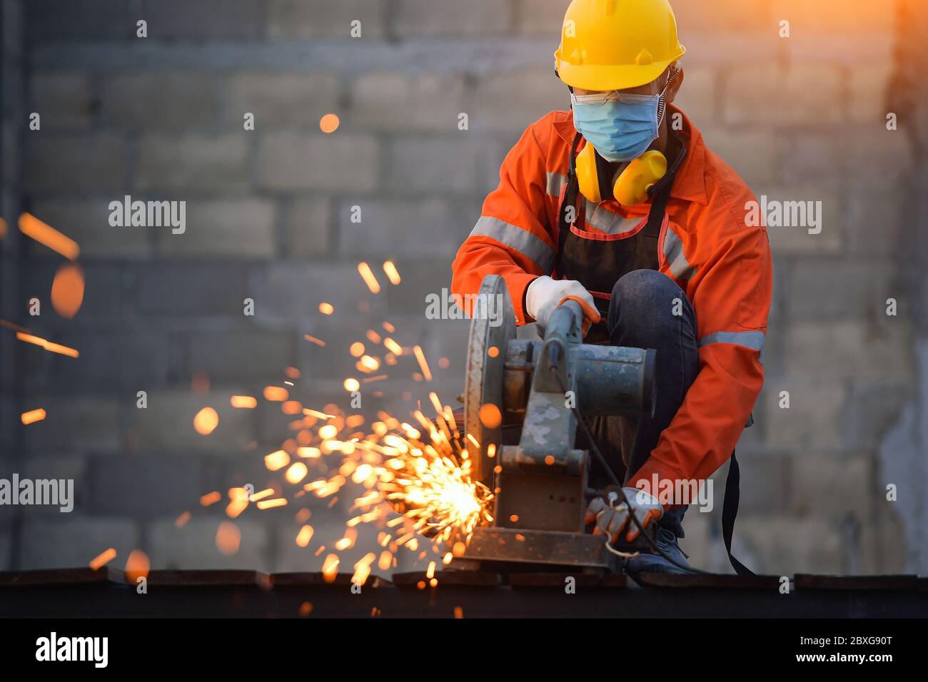 Industrial worker wearing a face mask cutting metal with a metal grinder Stock Photo