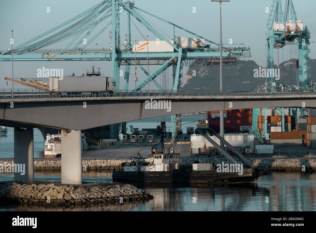 Sea transport and land transport. Activity in the commercial dock of Algeciras, Spain, with trucks and ships loading and unloading containers. Stock Photo