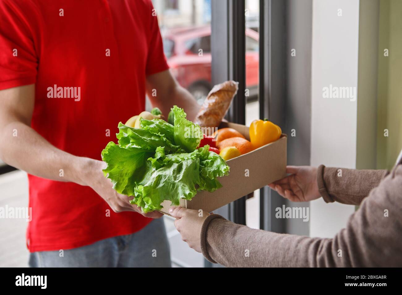 Products delivery directly from market. Hands of girl take box from courier Stock Photo