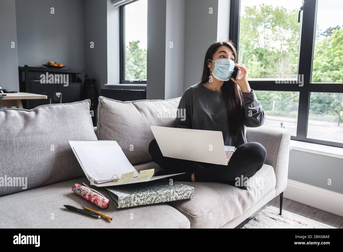 Woman sitting on a sofa working from home during lockdown Stock Photo