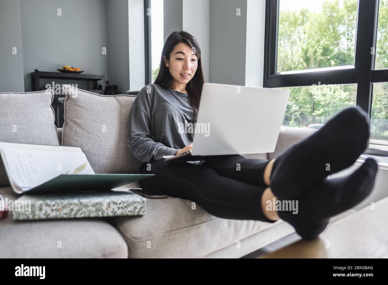 Woman sitting on a sofa working from home Stock Photo Alamy