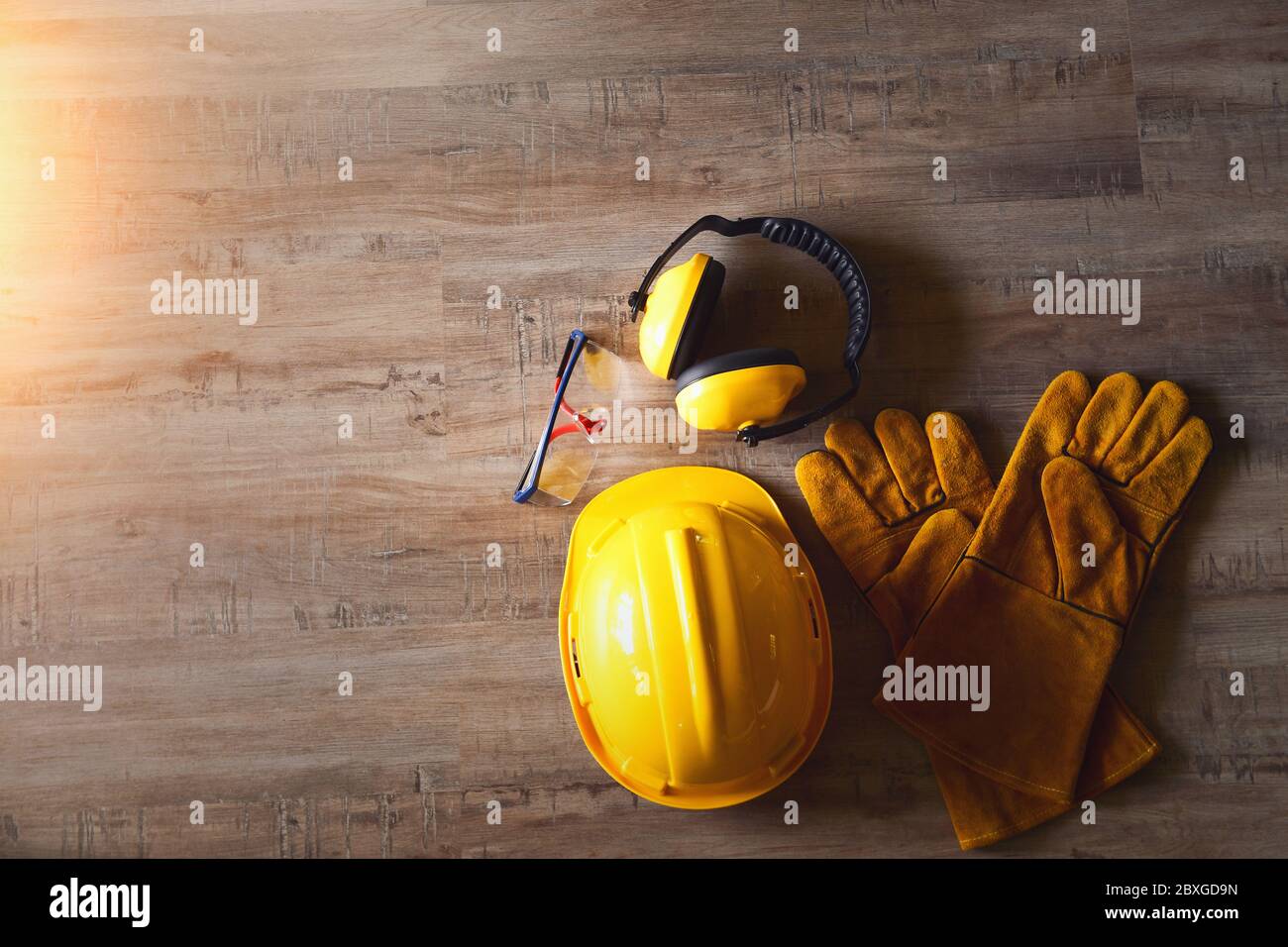 Safety helmet, goggles, gloves and ear defenders on a wooden table Stock Photo