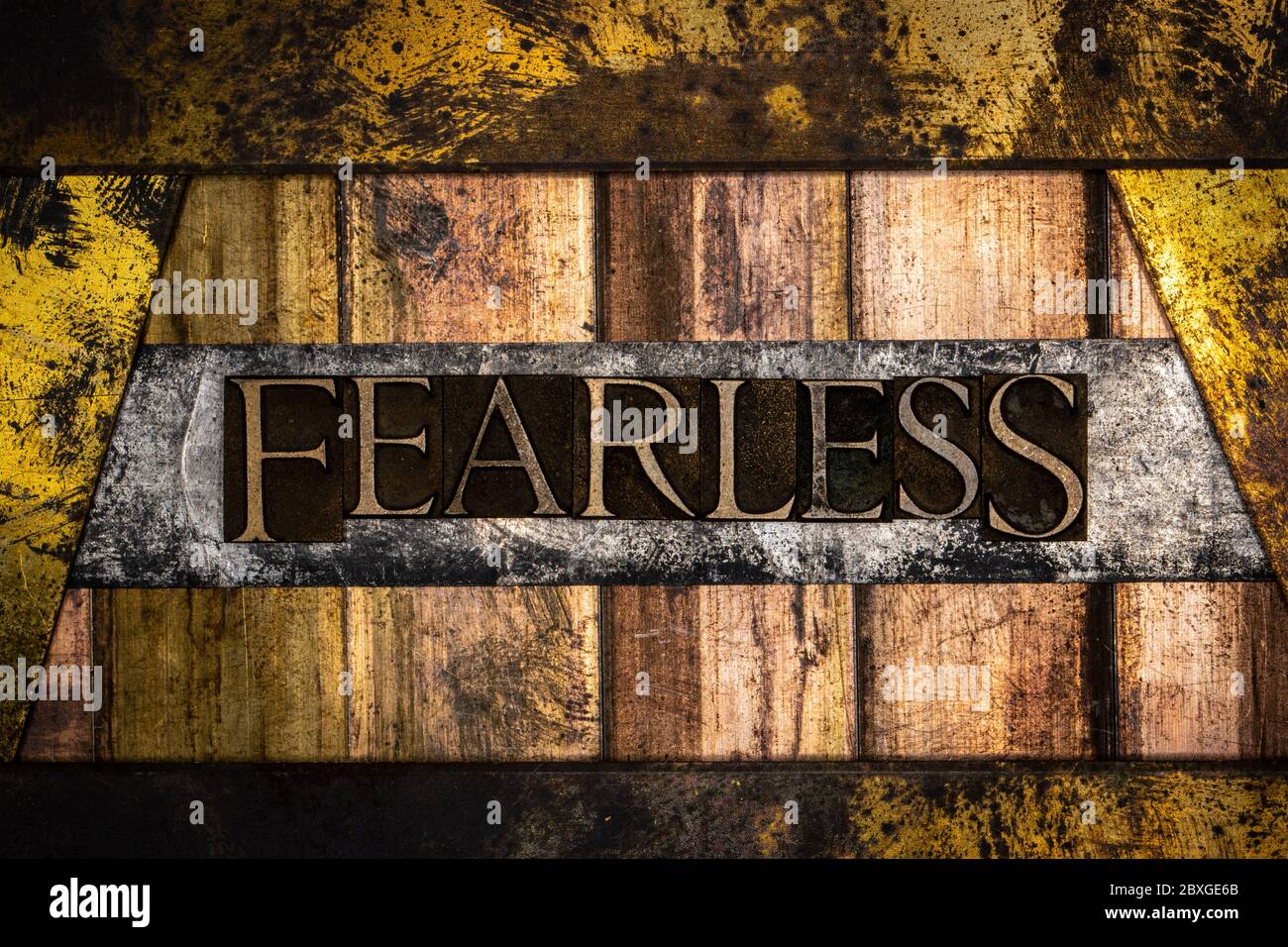 Photo of real authentic typeset letters forming Fearless text on vintage textured silver grunge copper and gold background Stock Photo