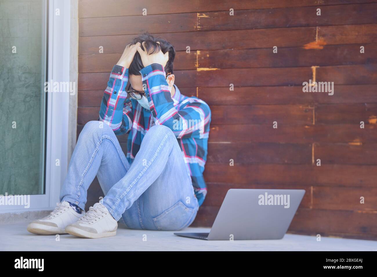 Desperate man sitting outdoors next to a laptop Stock Photo