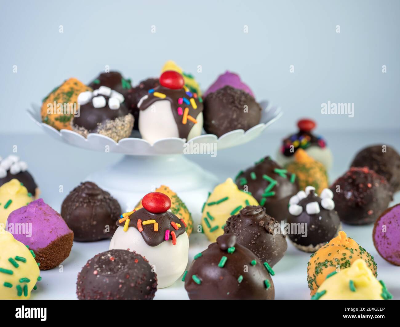 White raised platter filled with a variety of cake balls with more on the counter beneath it.  Banana split, S’mores, pineapple upside down cake, carr Stock Photo