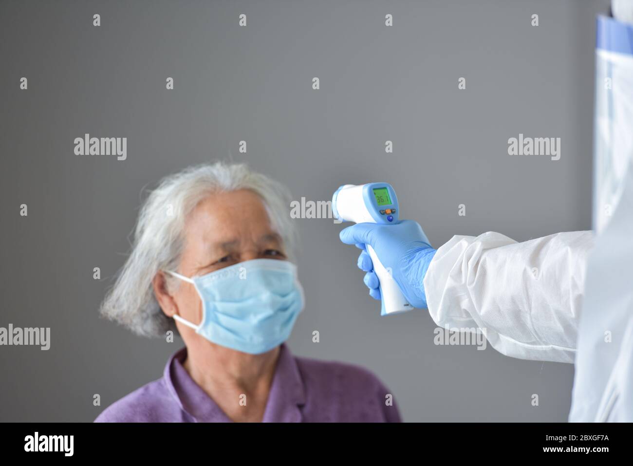 Doctor checking a woman's temperature using an infrared thermometer, Thailand Stock Photo