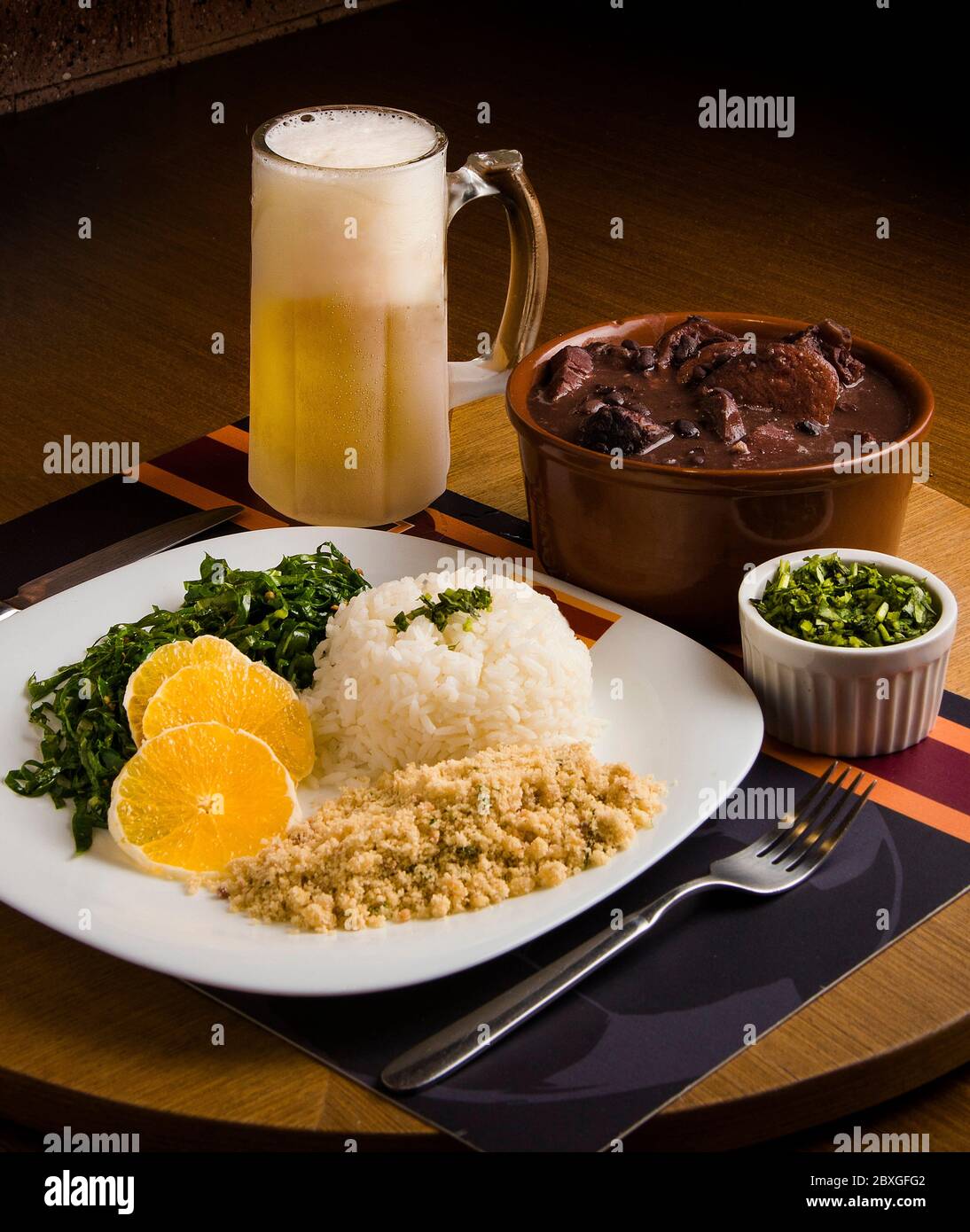 Feijoada stew with farofa, rice, kale and a glass of beer Stock Photo