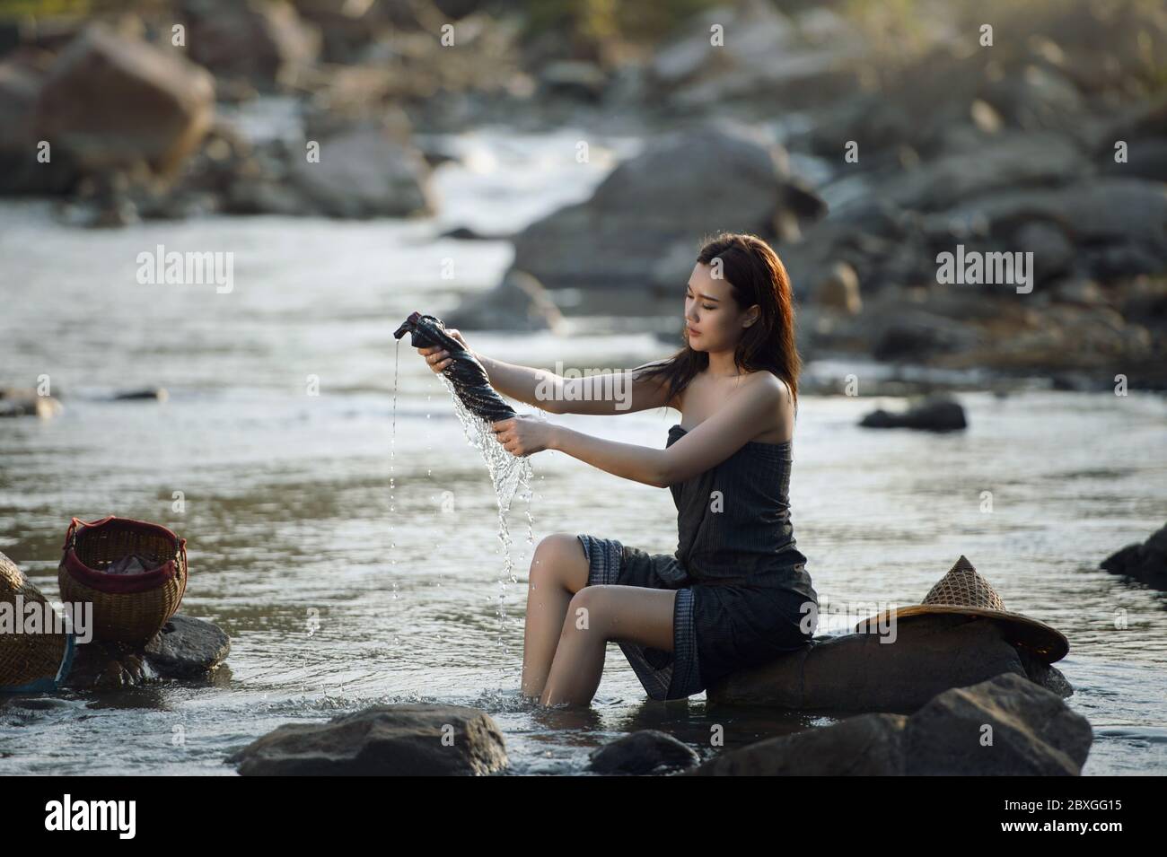 https://c8.alamy.com/comp/2BXGG15/beautiful-woman-sitting-on-a-rock-washing-her-clothes-in-the-river-thailand-2BXGG15.jpg