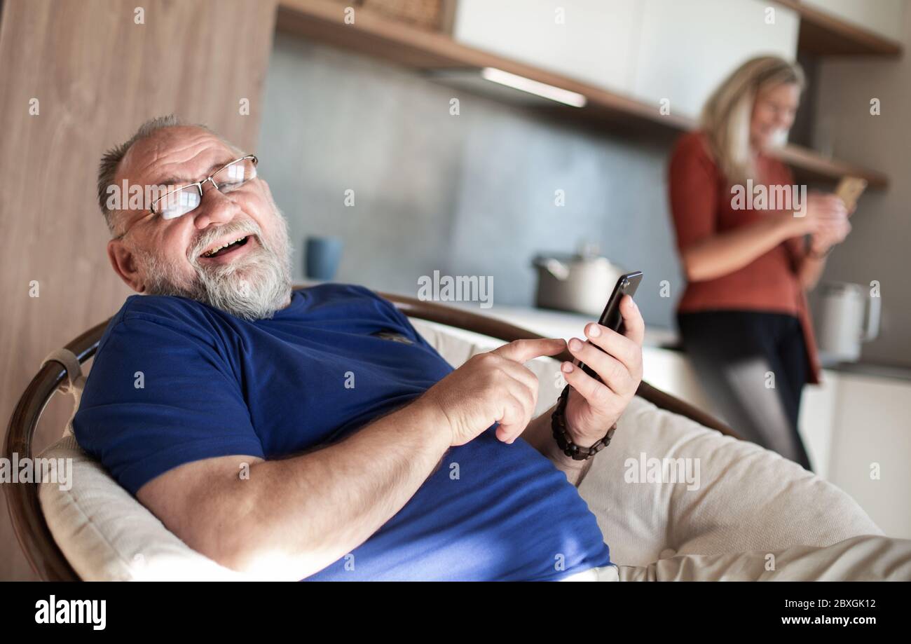 elderly man with a smartphone sitting in a home chair. Stock Photo