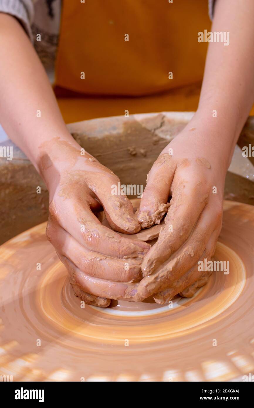 The hands of a teenager potter, making an earthen jar. Vertical Stock Photo