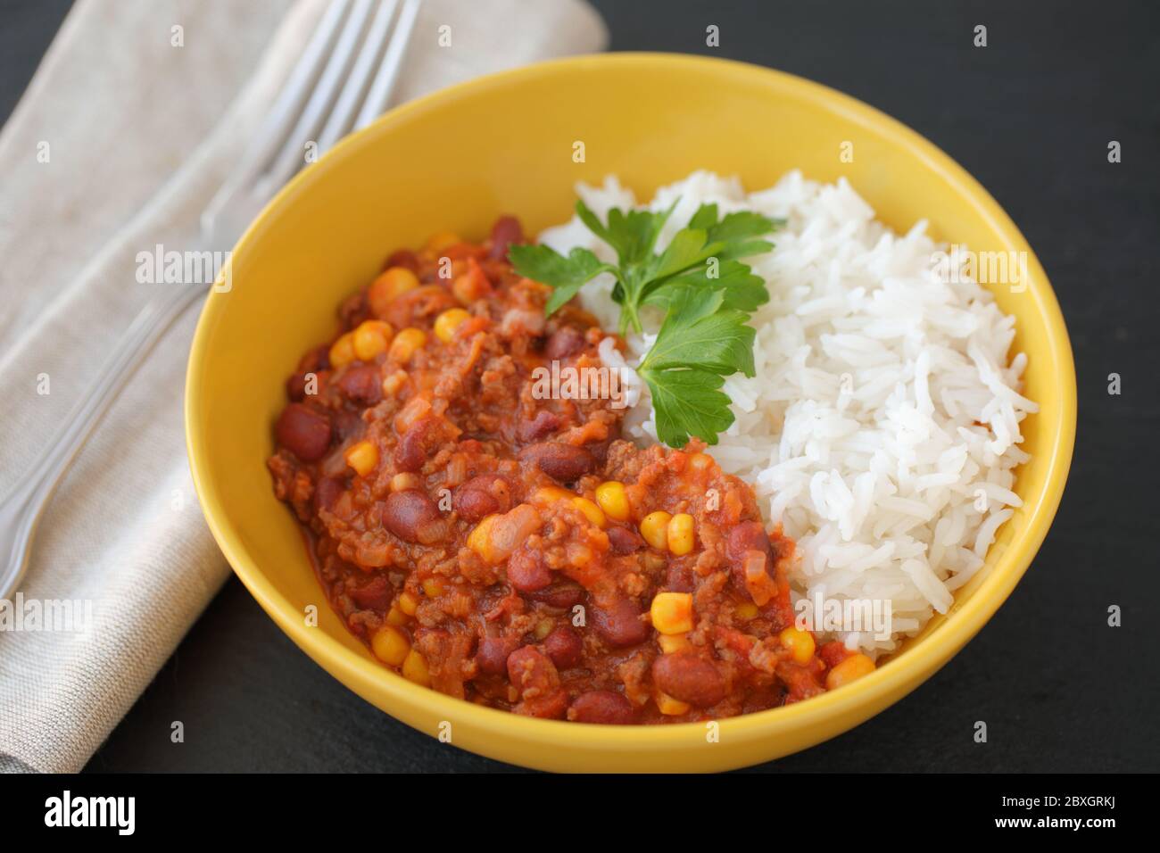 Chili con carne with long-grained rice decorated with a leaf of parsley closeup Stock Photo