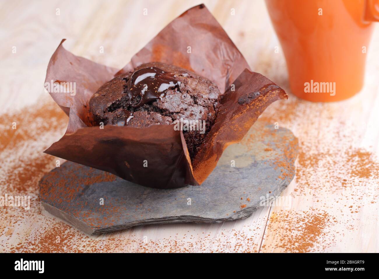 Chocolate muffin in a baking paper on a rustic table Stock Photo